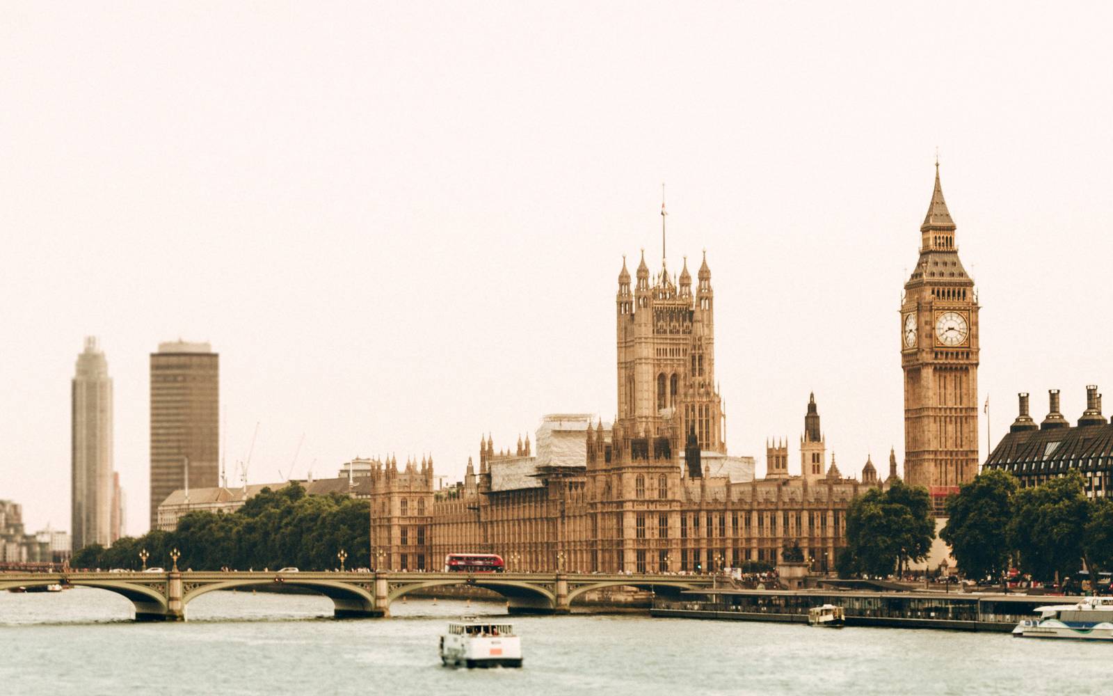 The River Thames in London with Westminster Bridge, the Palace of Westminster and the clock tower, a red double-decker bus crossing the bridge